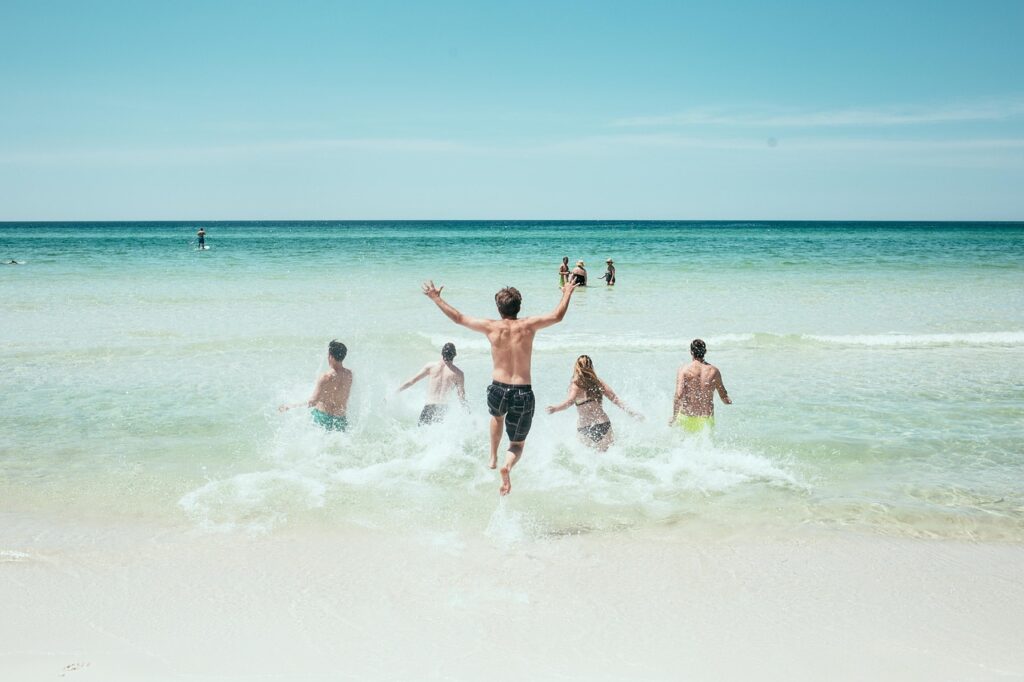 砂浜から、海に飛び込む若者5名の写真