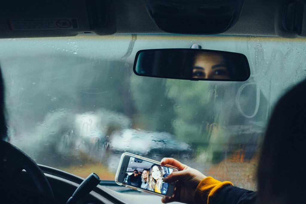 雨の中の車内で、スマホの自撮りをしている写真
