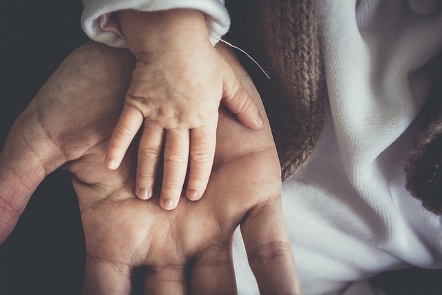 大人の手と、子供の手が重ねあっている画像。