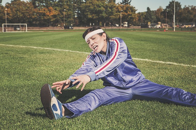 ３０代男性が、運動場でストレッチしている状況。
