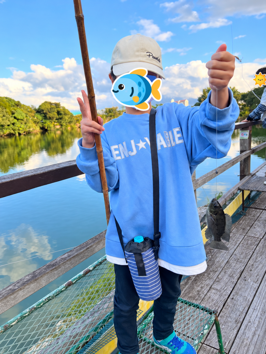 沖縄こどもの国のフィッシャーマンズデッキで魚を釣った子ども。顔は魚のスタンプで保護